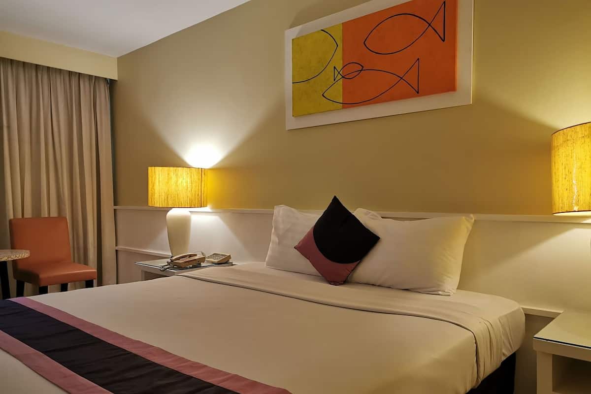 Une chambre d’hôtel avec un lit, une chaise, un bureau, une lampe et un tableau au mur.