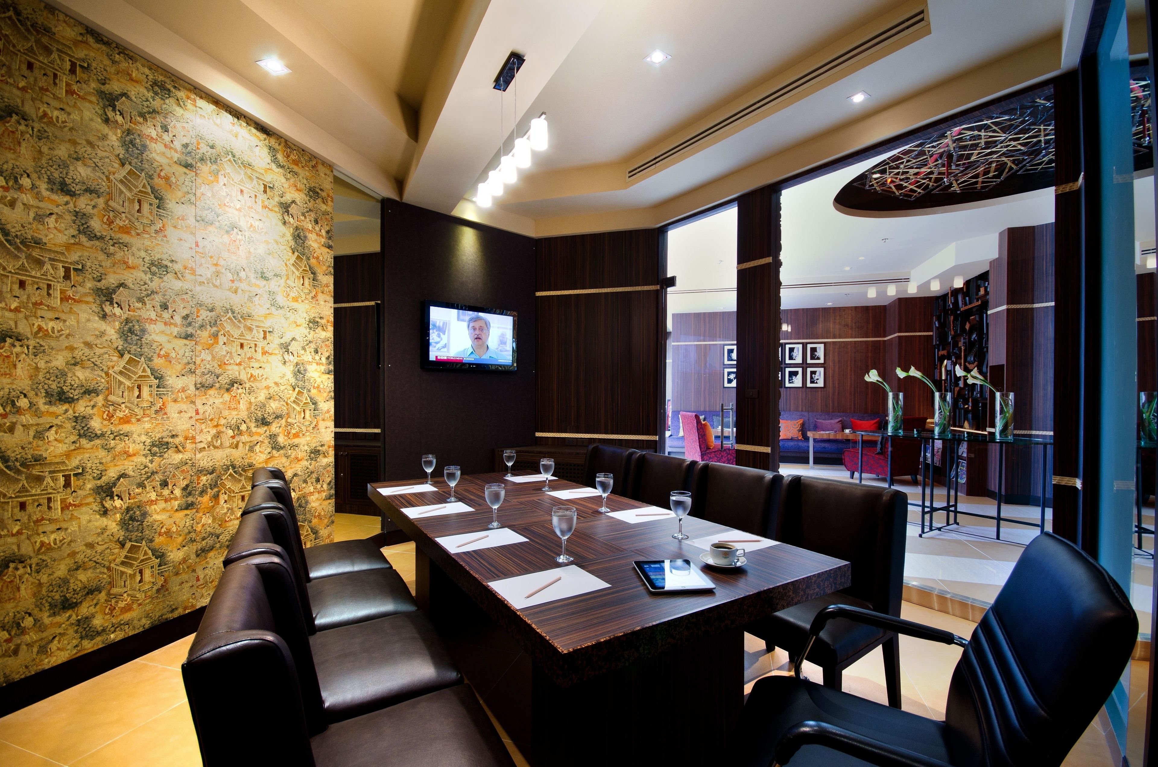 A conference room with a long table, chairs, and a television screen.