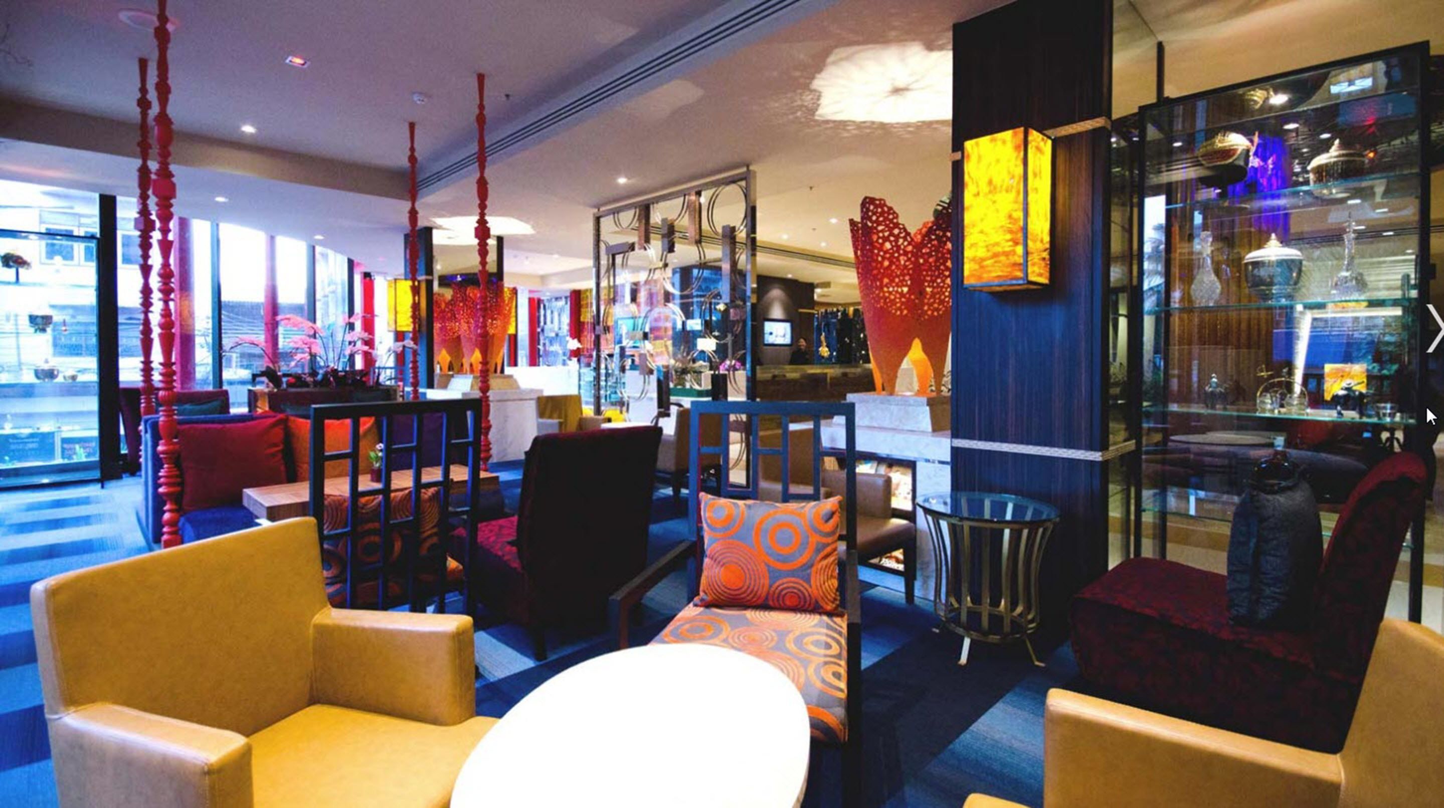 A modern lobby with seating areas, a reception desk, and a glass display case with decorative items.