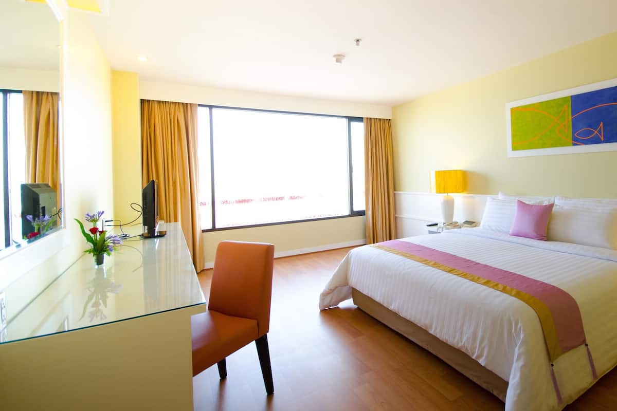 Une chambre d’hôtel comprenant un lit, une table de chevet, une chaise, un bureau et une grande fenêtre.