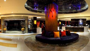 A modern lobby with a central seating area, a reception desk, and a large decorative column.