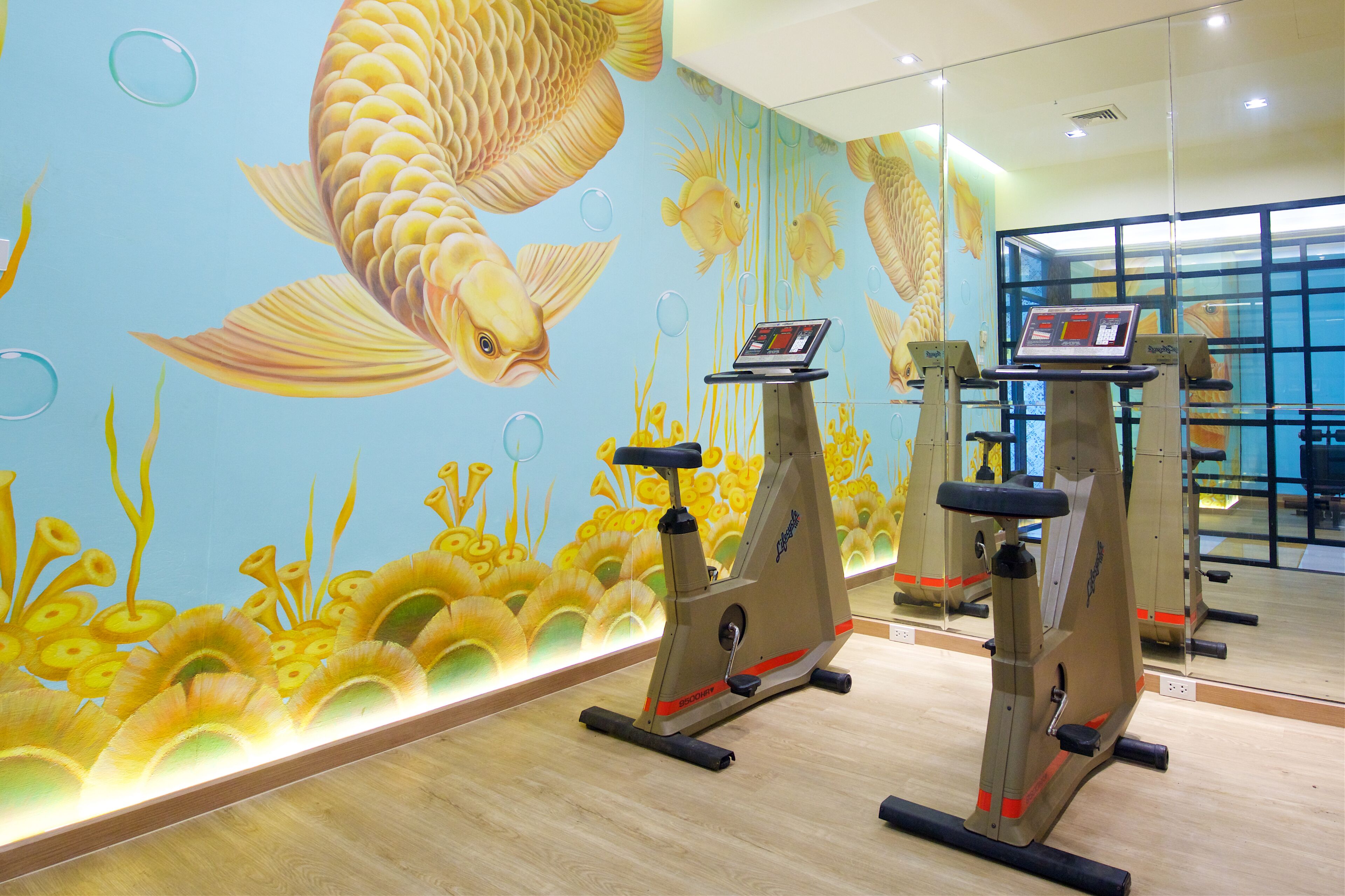 A gym with exercise bikes and a mural of fish on the wall.