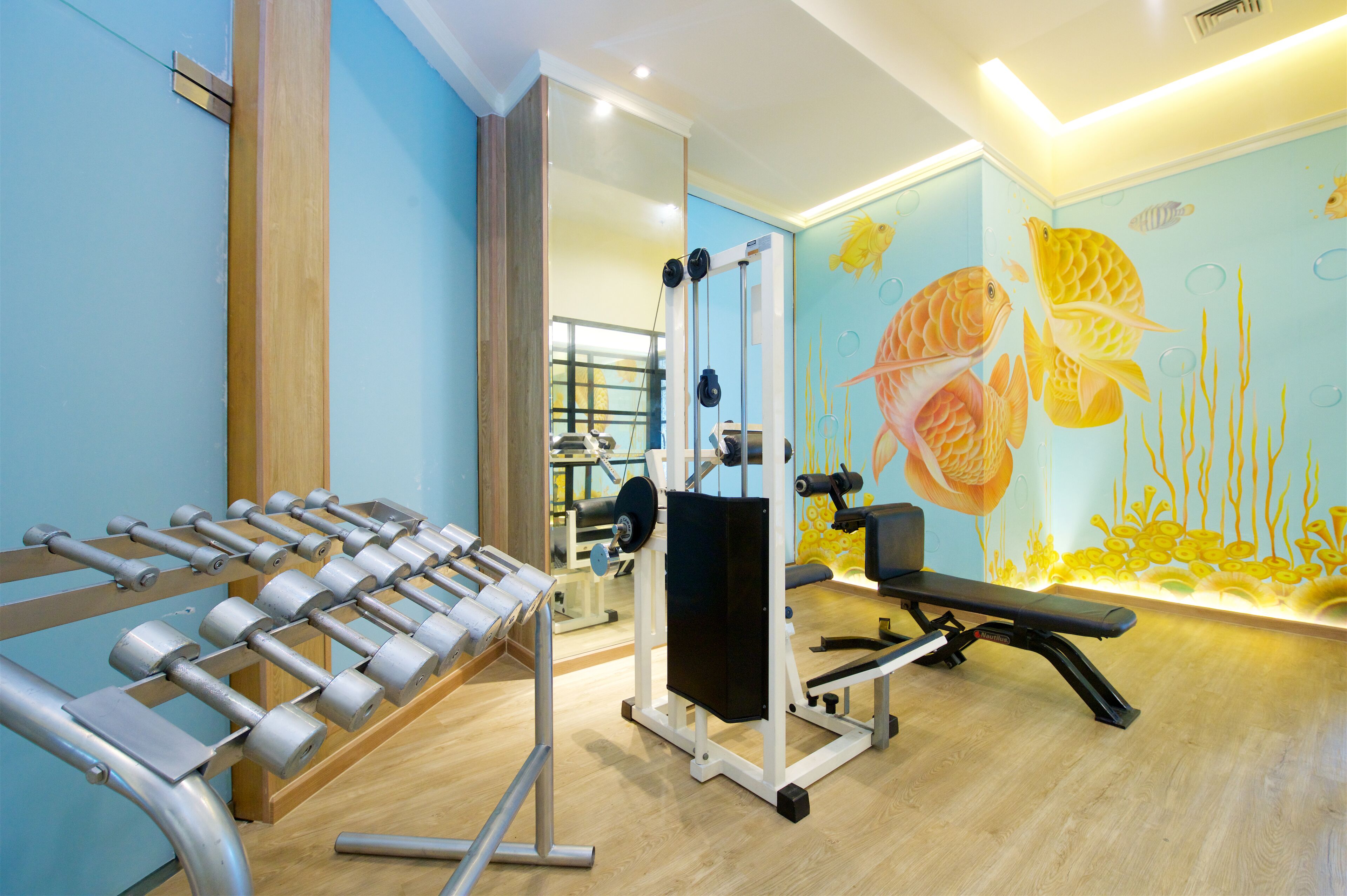 A gym with exercise equipment, a bench, and a wall mural.