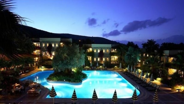 Un resort con una gran piscina, varias edificaciones y zonas de estar al aire libre.