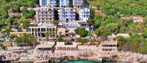 Un hôtel situé sur la côte, composé de plusieurs bâtiments, avec un rivage rocheux et une mer d’un bleu limpide.