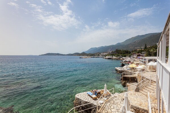 Un hôtel situé sur la côte, doté d’une terrasse et offrant une vue sur la mer.
