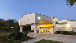 A modern building with a covered entrance, a large glass door, and a well-maintained lawn. - Days Inn by Wyndham San Antonio at Palo Alto (San Antonio)