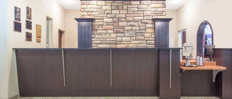 A reception area with a stone wall, dark reception desk, and framed awards on the wall.