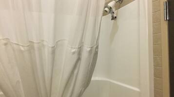 A bathroom with a shower curtain, a bathtub, and a tiled wall.