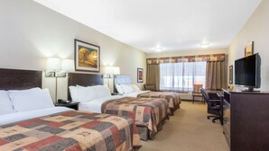 A hotel room with three beds, a desk with a television, and a window with curtains. - Ramada by Wyndham Pincher Creek (Pincher Creek)