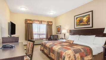 A hotel room with a bed, a desk with a telephone, a chair, a television, and a painting on the wall.