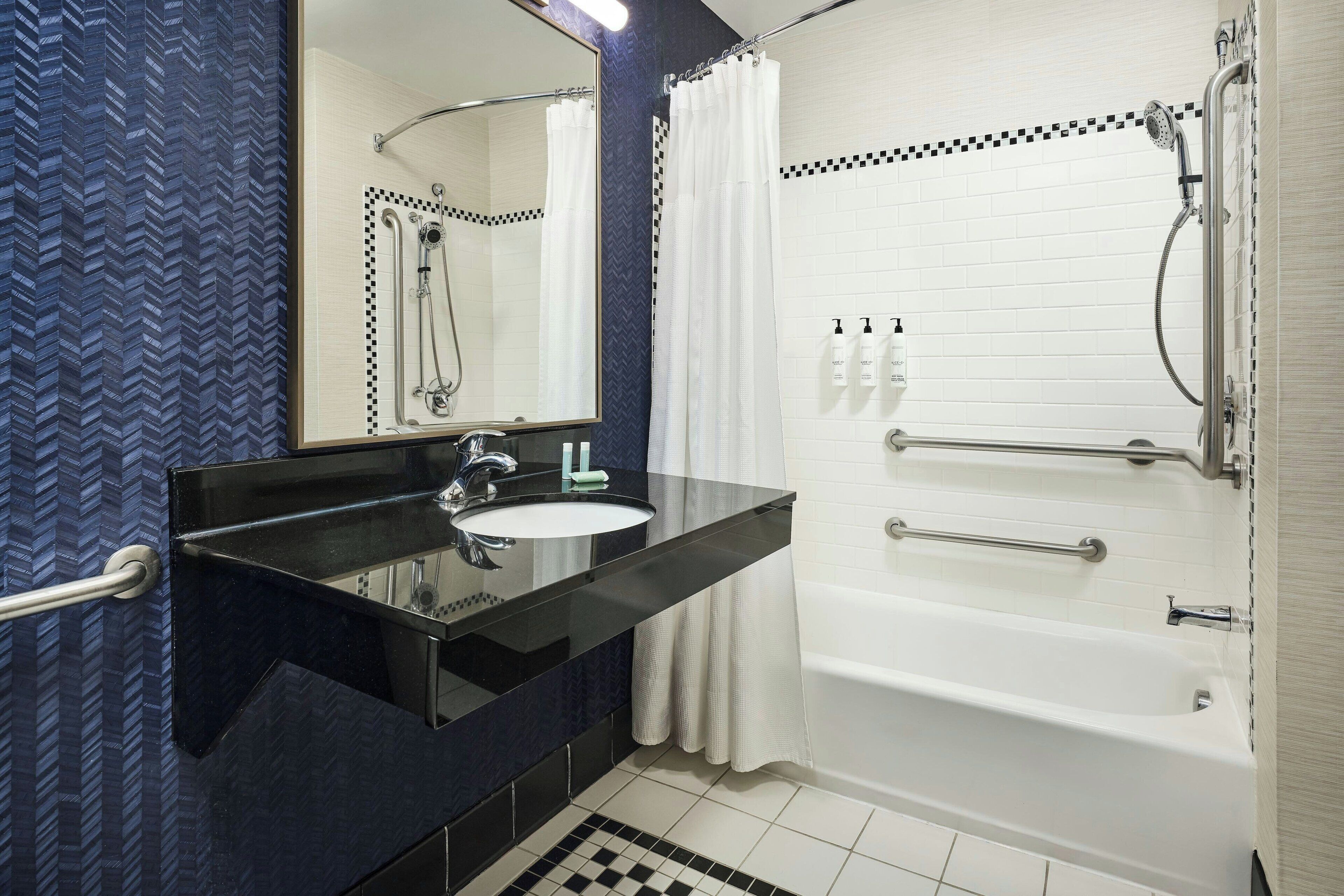 A bathroom with a black vanity, white sink, and a bathtub.