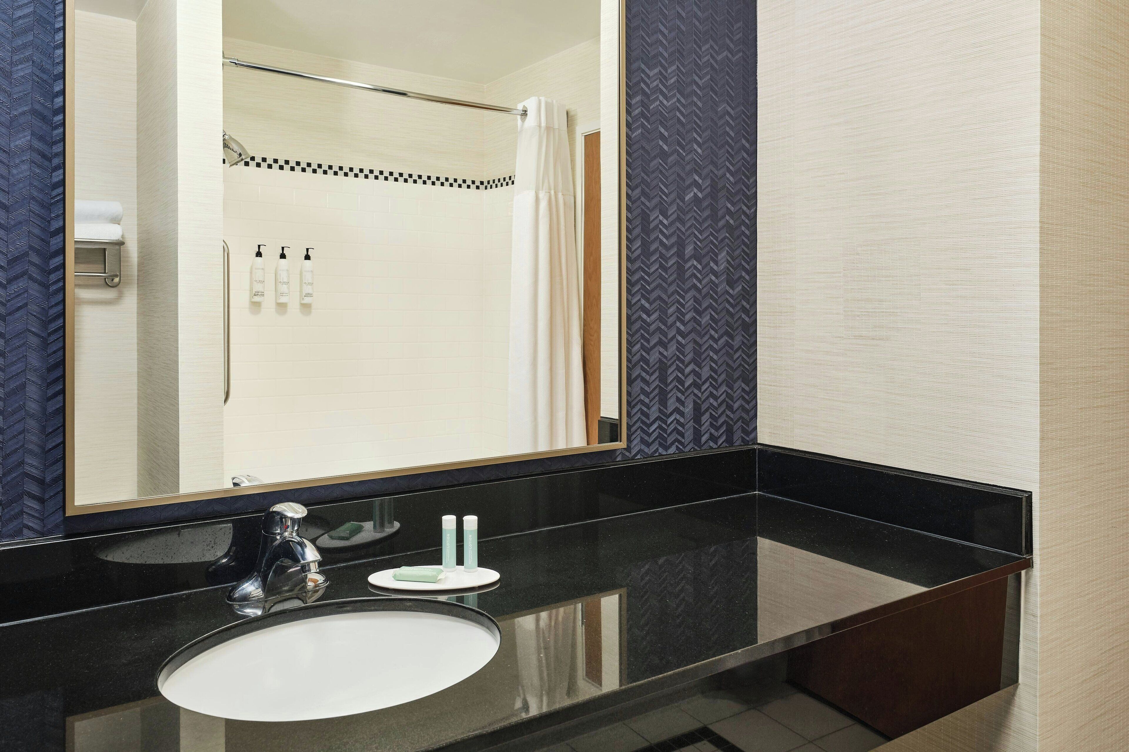 A modern bathroom with a black countertop, a round sink, and a large mirror.