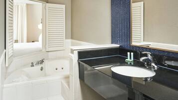Un baño moderno con una bañera, un lavabo y un espejo grande.