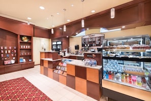 L’intérieur d’un café, avec un comptoir, des vitrines et un panneau affichant le menu.