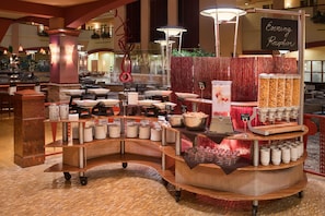 A buffet setup with various food stations, including a salad bar and a beverage station.
