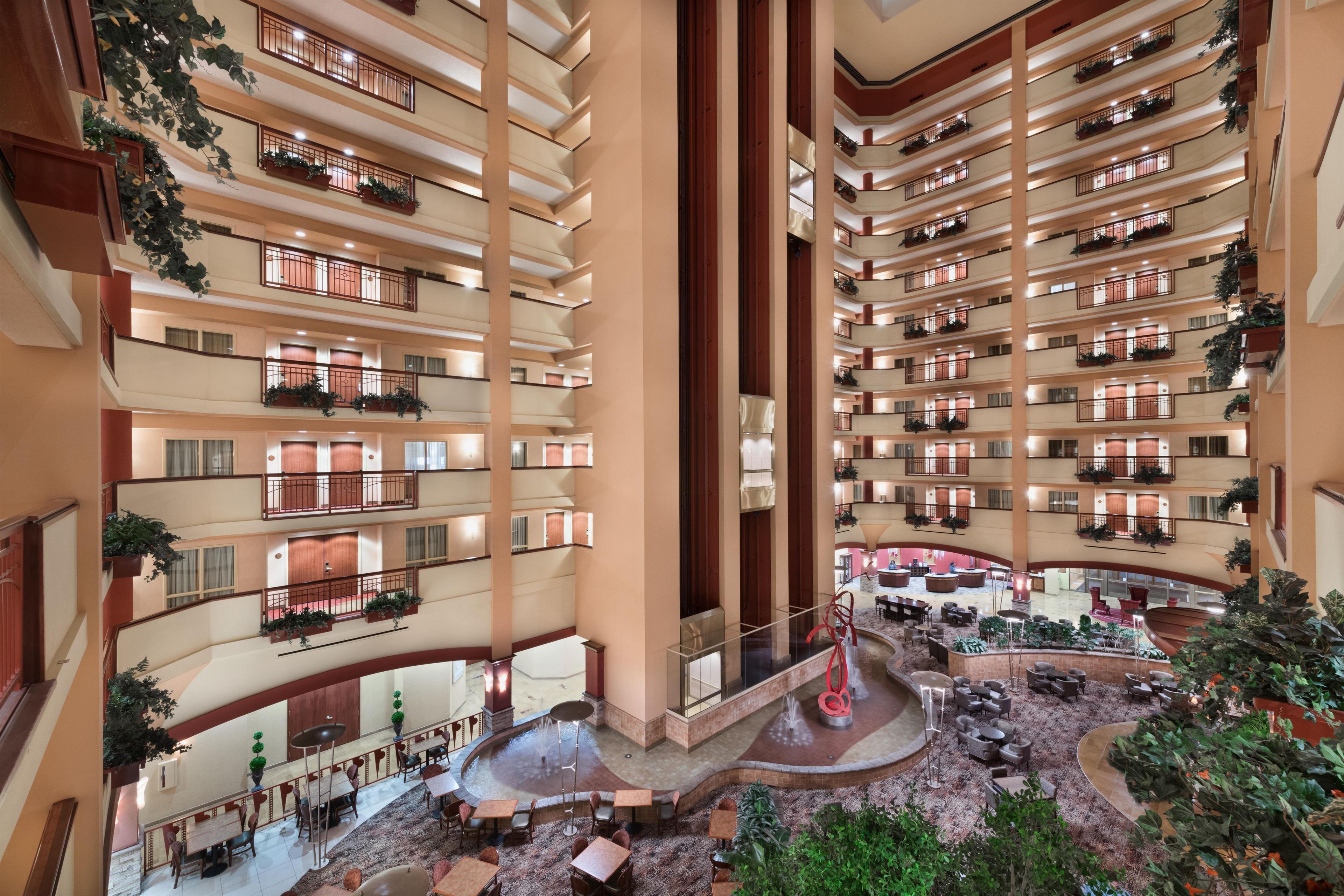Ein mehrgeschossiges Hotel-Atrium mit Balkonen, einer zentralen Fontäne und einer Sitzecke.