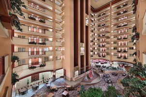 A multi-level hotel atrium with balconies, a central fountain, and a seating area.
