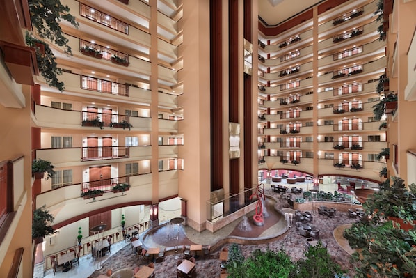 Un atrium d’hôtel à plusieurs niveaux, doté de balcons, d’une fontaine centrale et d’un espace détente.