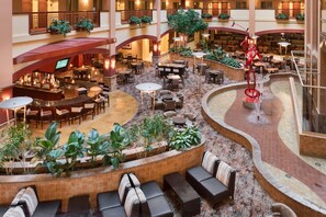 A hotel atrium with multiple dining areas, a bar, and a fountain.