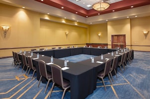 Un salón de conferencias con una mesa larga, sillas y botellas de agua.