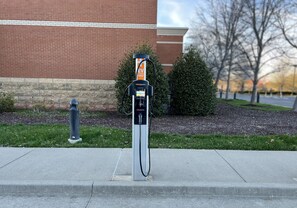 An electric vehicle charging station in front of a brick building.