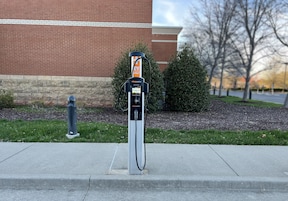 Una estación de carga para vehículos eléctricos frente a un edificio de ladrillo.