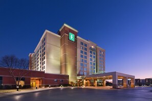 A multi-story hotel with a prominent 'E' logo, a parking lot, and a well-lit entrance.