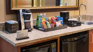 A hotel room's kitchenette with a coffee maker, water bottles, snacks, and a coffee cup. - Embassy Suites by Hilton Nashville SE Murfreesboro (Murfreesboro)