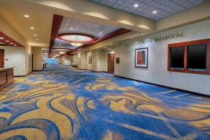A hotel corridor with a patterned carpet, a ceiling with recessed lighting, and a sign for the Mirabella Grand Ballroom.