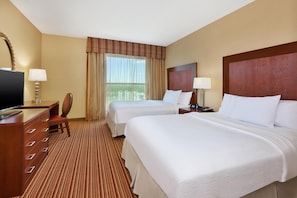 A hotel room with two beds, a desk, a chair, a television, and a window with curtains. - Embassy Suites by Hilton Nashville SE Murfreesboro (Murfreesboro)