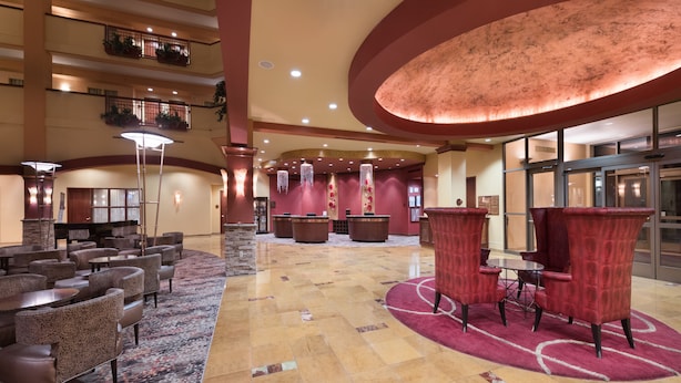 A spacious lobby with multiple seating areas, including round tables and chairs, and a large, circular red carpet. - Embassy Suites by Hilton Nashville SE Murfreesboro (Murfreesboro)