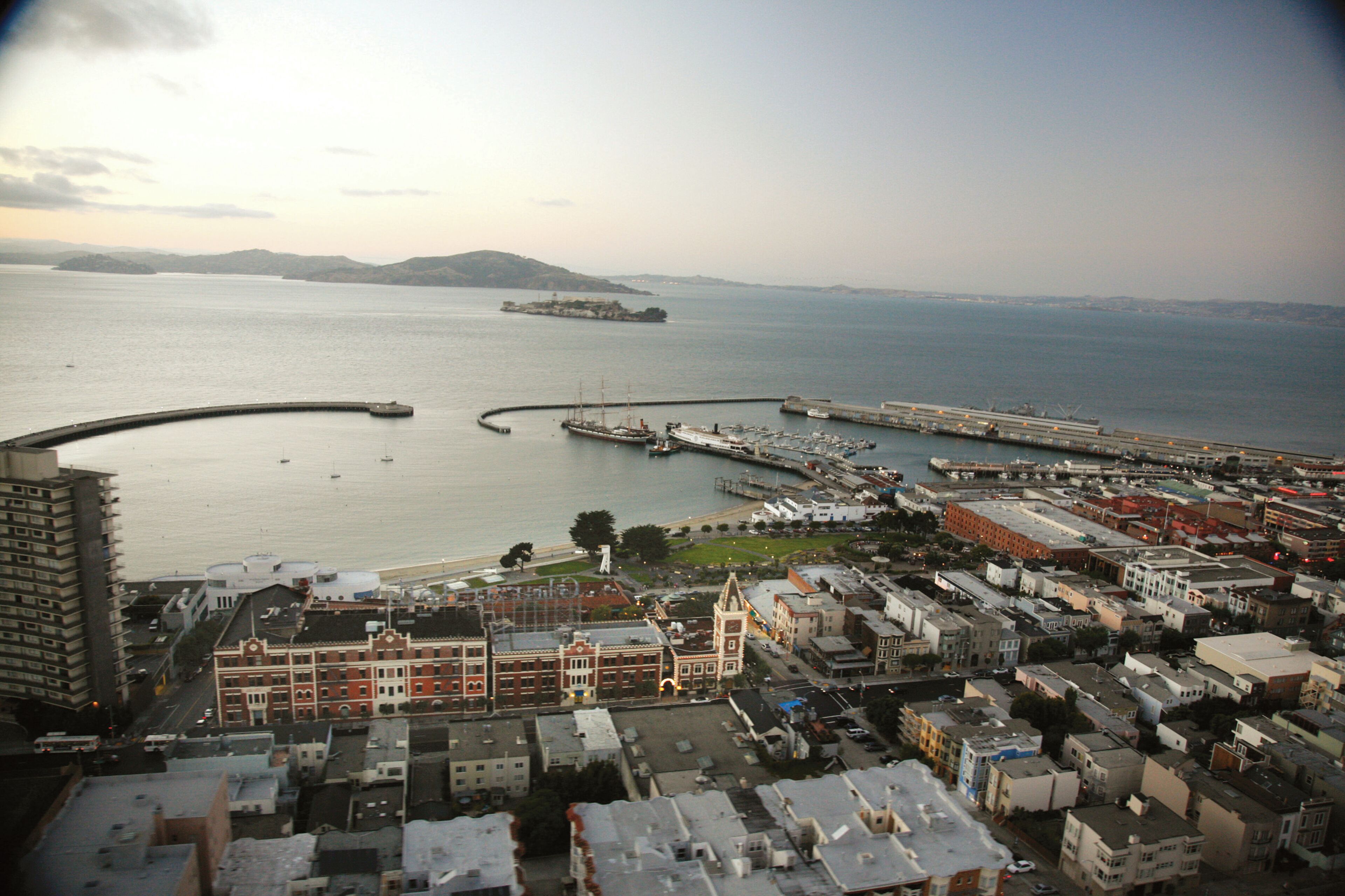 Paisagem costeira com uma marina, edifícios e um grande navio ao fundo.