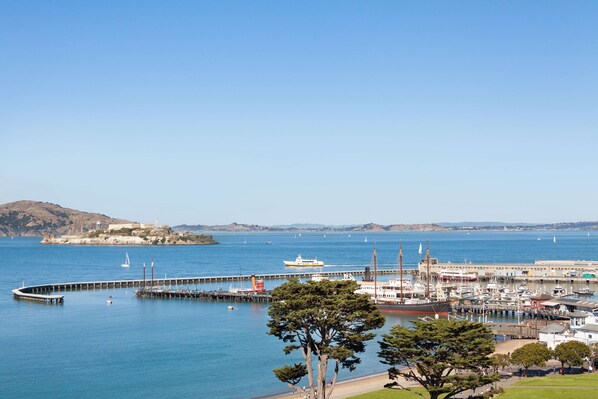 Un port de plaisance sur la côte, avec des bateaux, une jetée et un phare en arrière-plan.
