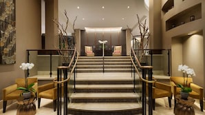 A grand staircase with a modern design, flanked by two chairs and two potted plants. - Fairmont Heritage Place, Ghirardelli Square (San Francisco)