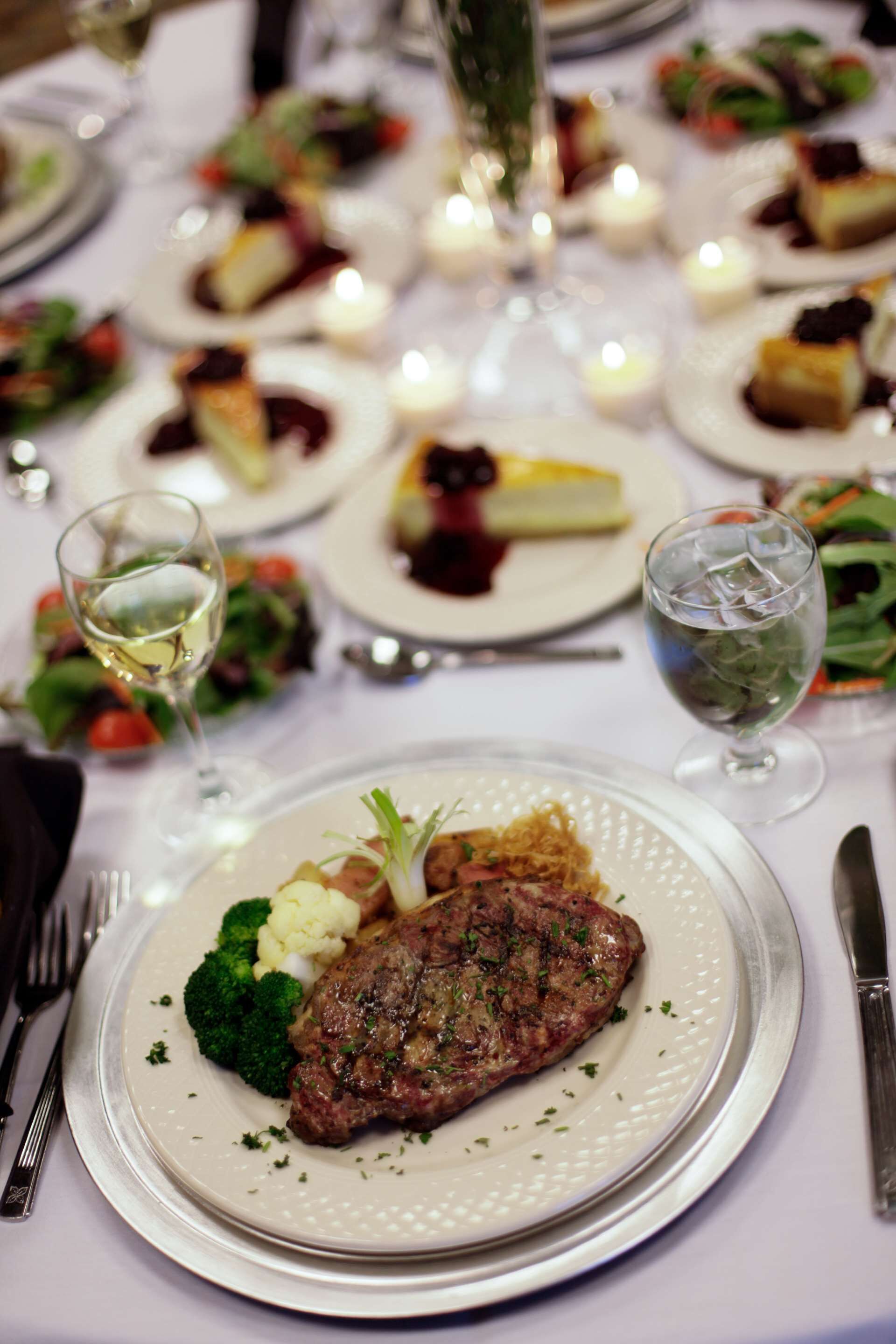 Ein Esstisch mit gedeckten Tellern, darunter Steak, Gemüse und Desserts.
