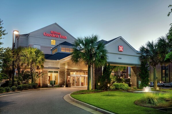 A Hilton Garden Inn with a modern design, featuring a large entrance, well-maintained lawn, and a clear view of the parking area.