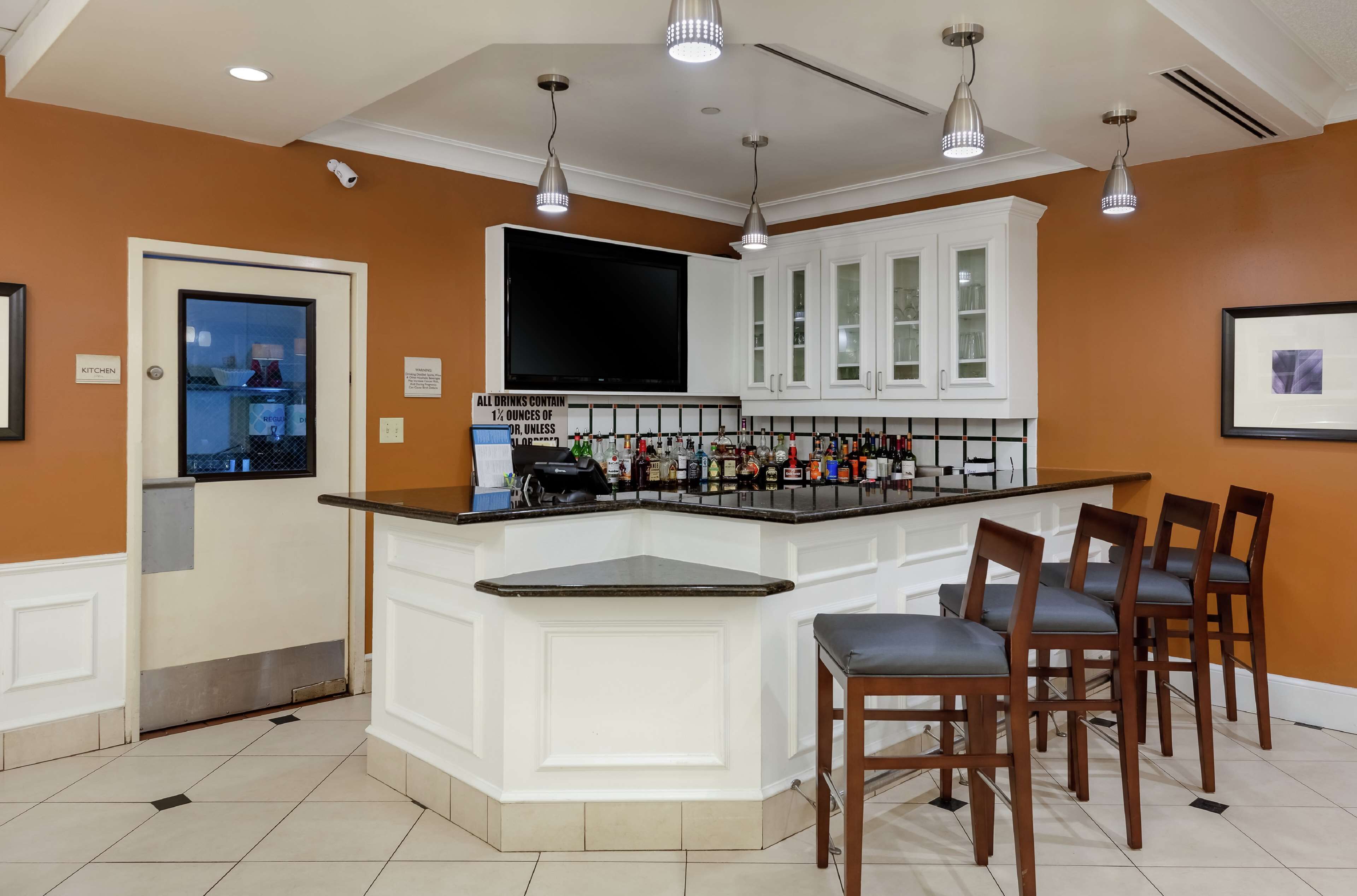 Una cocina con barra, armarios blancos y un televisor de pantalla plana grande.