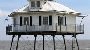 Un bâtiment blanc, d’un seul étage, doté d’un balcon sur pilotis au-dessus de l’eau.