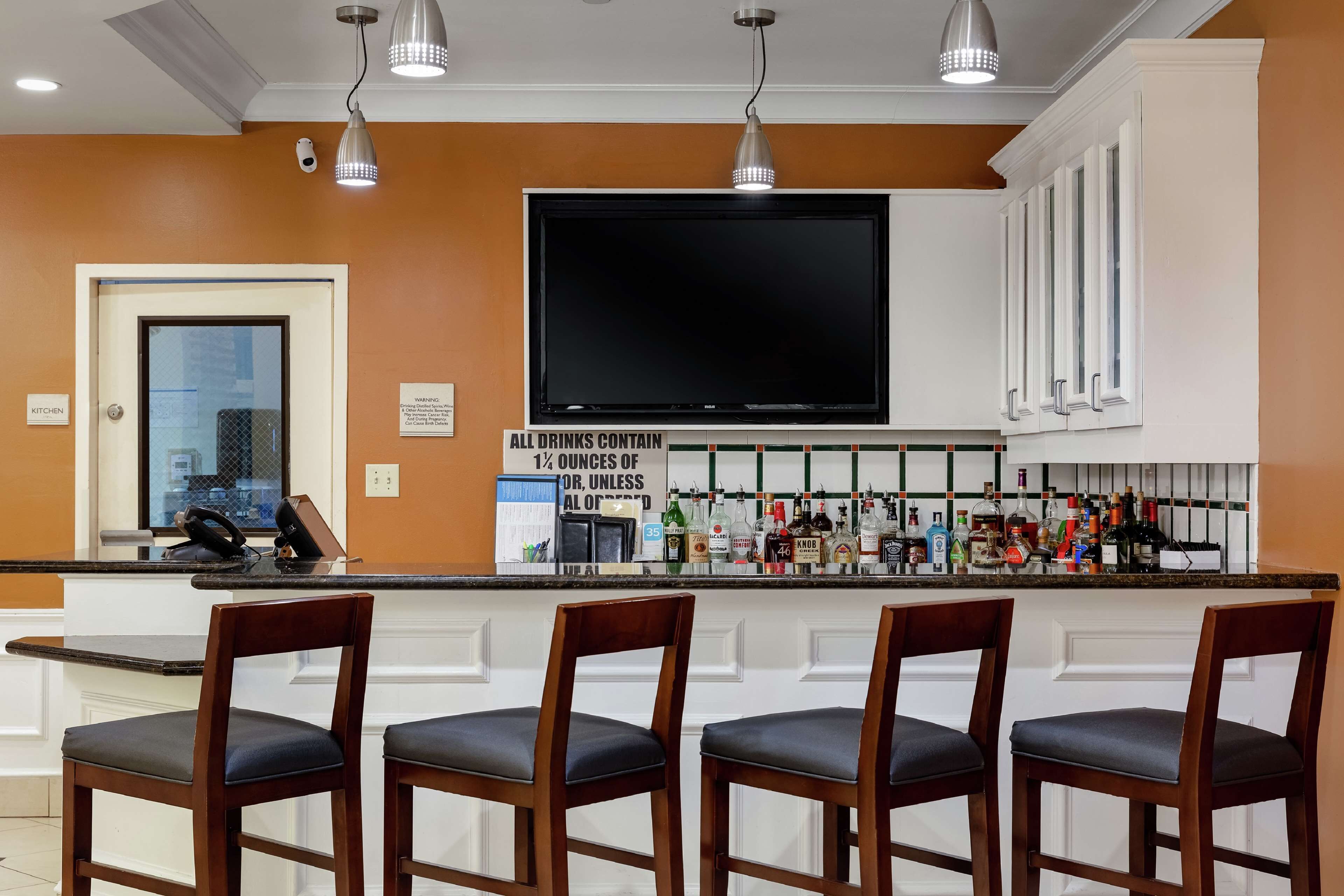 A bar area with a flat-screen TV, bar stools, and a variety of liquor bottles.