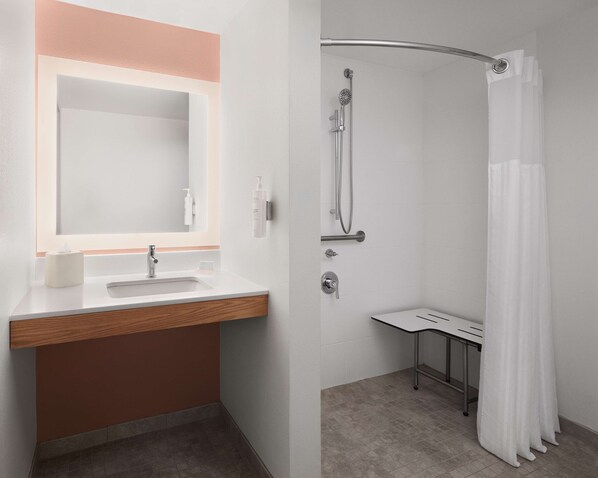 A modern bathroom with a sink, mirror, and shower.