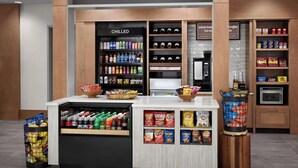 A store named 'The Shop' with a chilled section, snack aisle, and a coffee station.