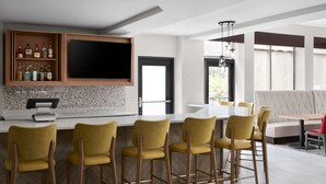 A modern kitchen with a bar area, bar stools, and a dining table with chairs.