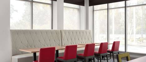 A dining area with a long table, red chairs, and a cushioned bench.
