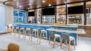 Un espace bar doté d’un long comptoir, de nombreux tabourets et d’une variété de bouteilles et de verres exposés sur des étagères.