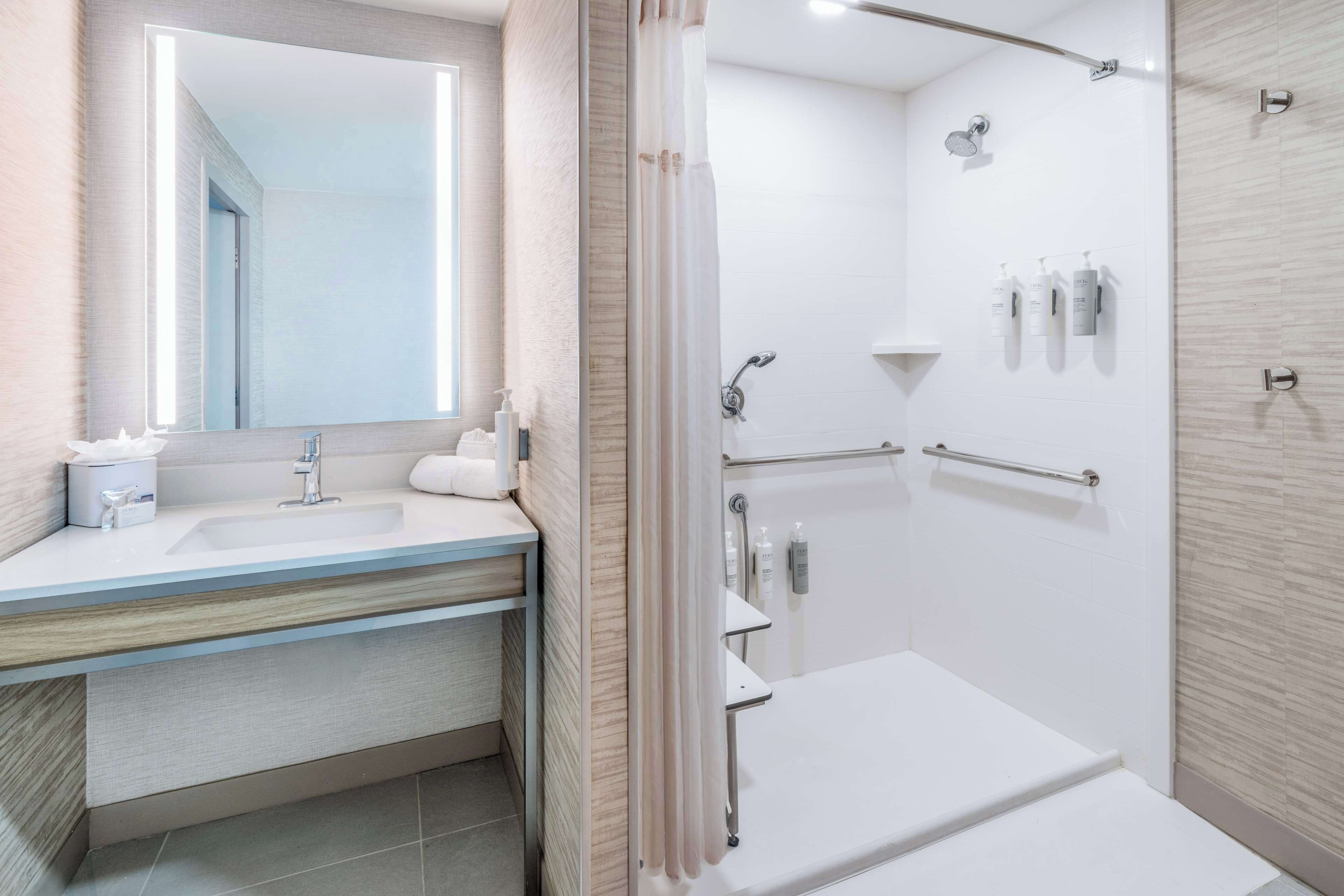 Une salle de bain moderne avec un grand miroir, un lavabo, une douche et des toilettes.