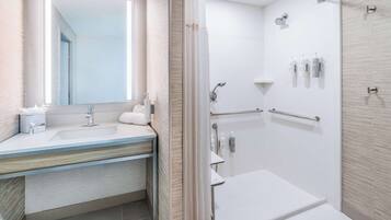 Une salle de bain moderne avec un grand miroir, un lavabo, une douche et des toilettes.