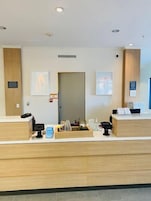 Un mostrador de recepción con detalles de madera, una puerta y obras de arte enmarcadas en las paredes.