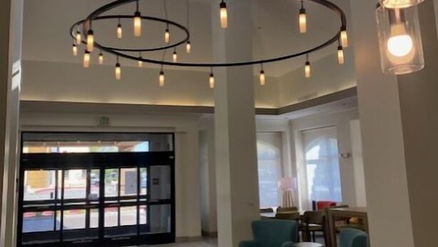 A spacious lobby with high ceilings, large windows, and modern pendant lighting. - Hilton Garden Inn Palmdale (Palmdale)
