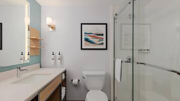 A modern bathroom with a glass shower enclosure, a white toilet, and a large mirror.